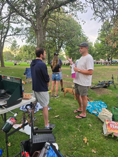 Jake holding petition sections, talking with a group of neighbors on the lawn at City Park Jazz