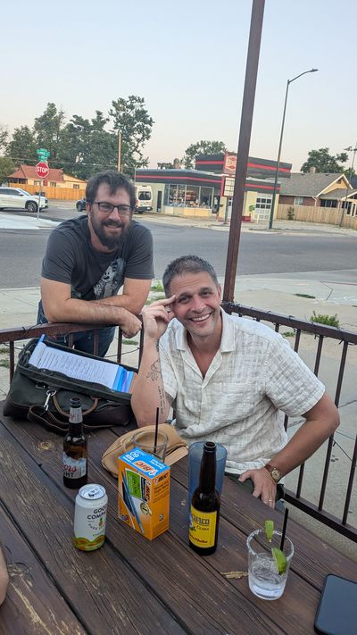 Jake and a neighbor talking over the petition binder at a picnic table on the Rocky Top Tavern patio